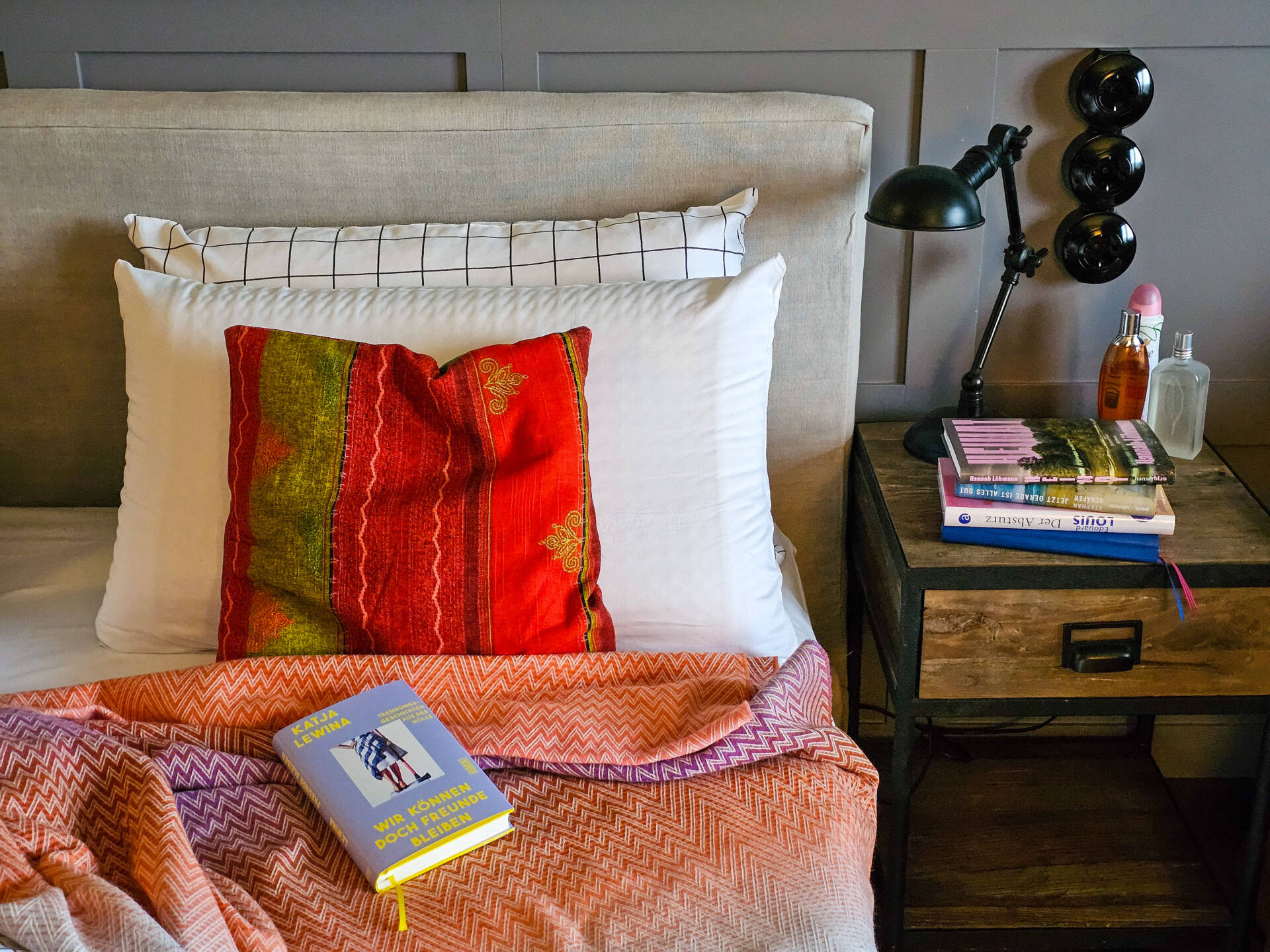 Hotelbett und Nachttischchen mit Büchern